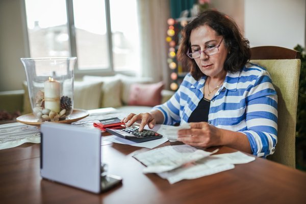 Person sitting at a desk and working on paperwork with a calculator.