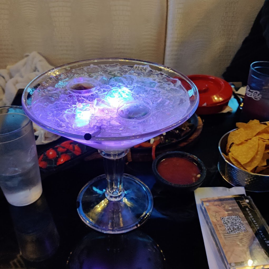 A blue alcoholic drink with glowing blue ice cubes.