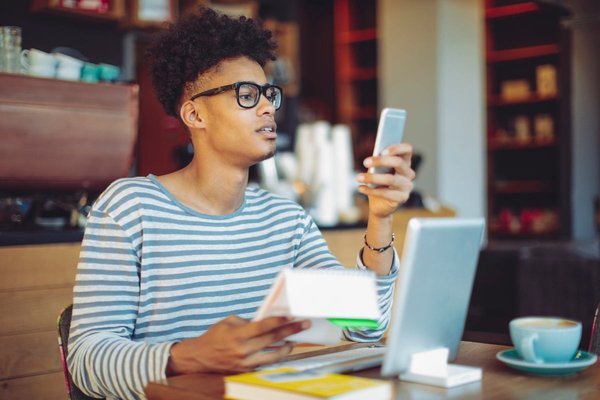 Person looks at phone and paperwork at desk.