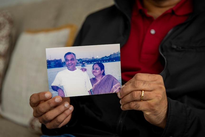 A man holding a photograph of his parents.