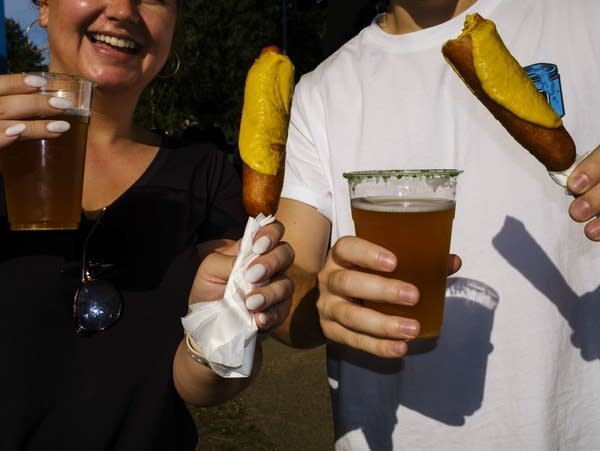 Two person share a corn dogs and beer