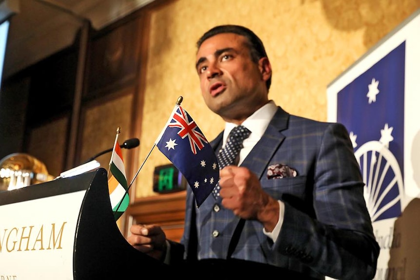 A man wearing a suit standing at a podium delivering a speech.