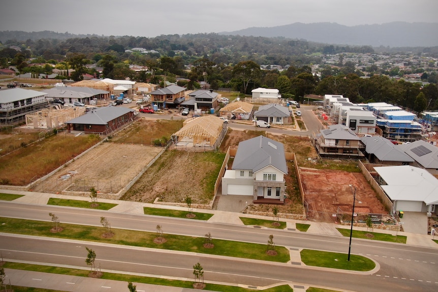 An aerial photo of a new housing estate with empty blocks and several new houses being built.