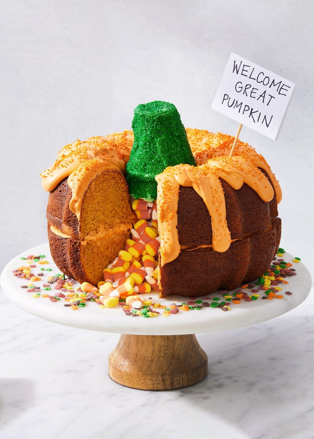 two pumpkin bundt cakes stacked on each other, filled with candy corn, and decorated to look like a pumpkin