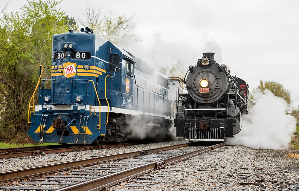 Steam locomotive next to blue high-nosed diesel