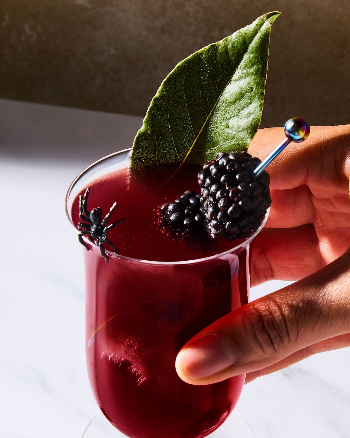 deep red cocktail topped with blackberries and bay leaves