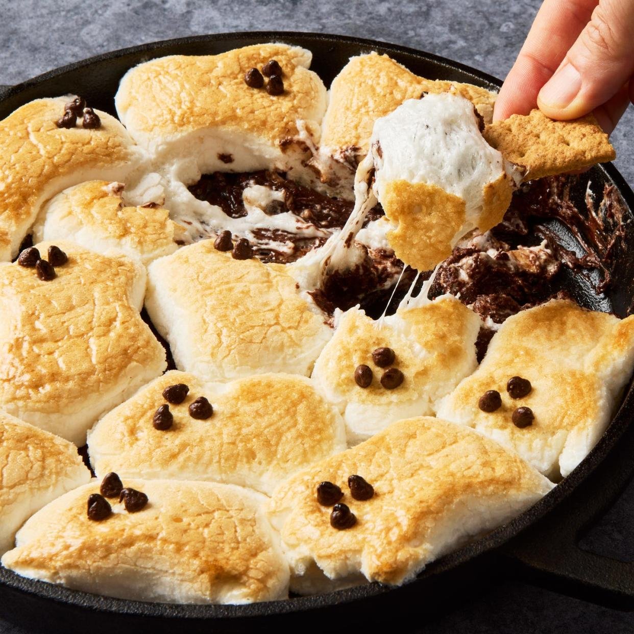 s'mores dip with ghost marshmallows on top served with graham crackers