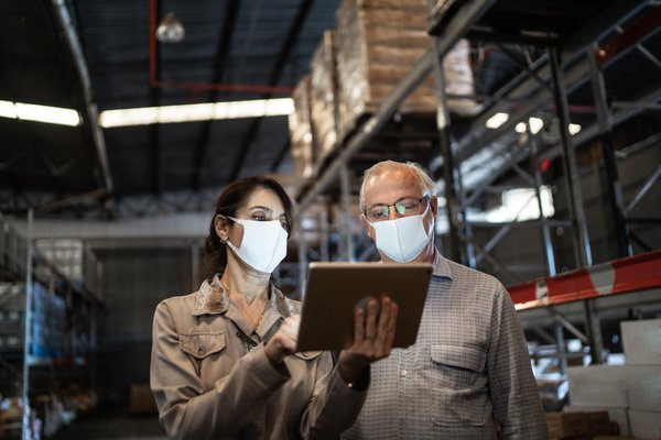 People checking inventory on tablet in storage warehouse.