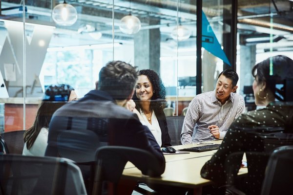 Financial service workers have a group meeting sitting at a table.