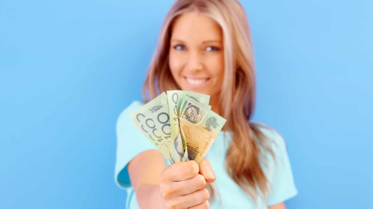 A smiling woman with a handful of $100 notes, indicating strong dividend payments