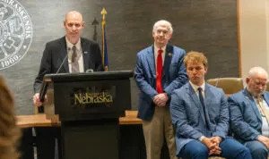 Neal Schnoor, at podium, is announced as priority candidate for the next University of Nebraska at Kearney chancellor. To his right are NU President Jeffrey Gold, UNK Student Regent Sam Schroeder and Regent Paul Kenney of Amherst. April 23, 2025. (Zach Wendling/Nebraska Examiner)