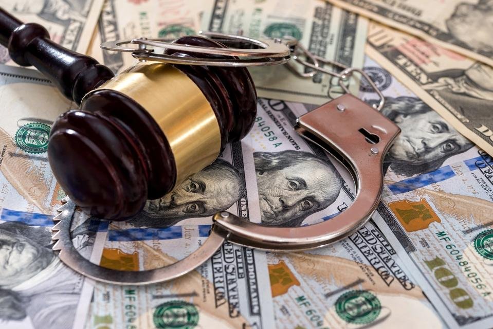 Steel handcuffs with judge's gavel on dollar banknotes
