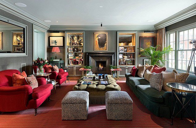 A reception room with a cast-iron fireplace, large window and two floor to ceiling bookcases