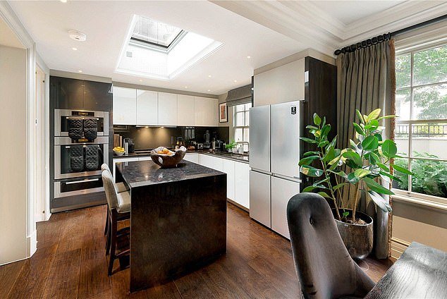 The open plan kitchen features a black marble island and worktops with a skylight window