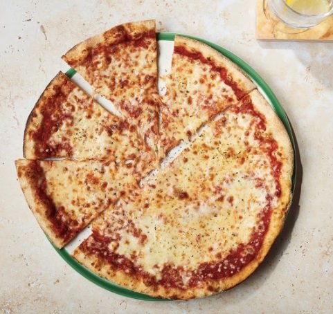 A large cheese pizza with several slices removed, served on a green plate.