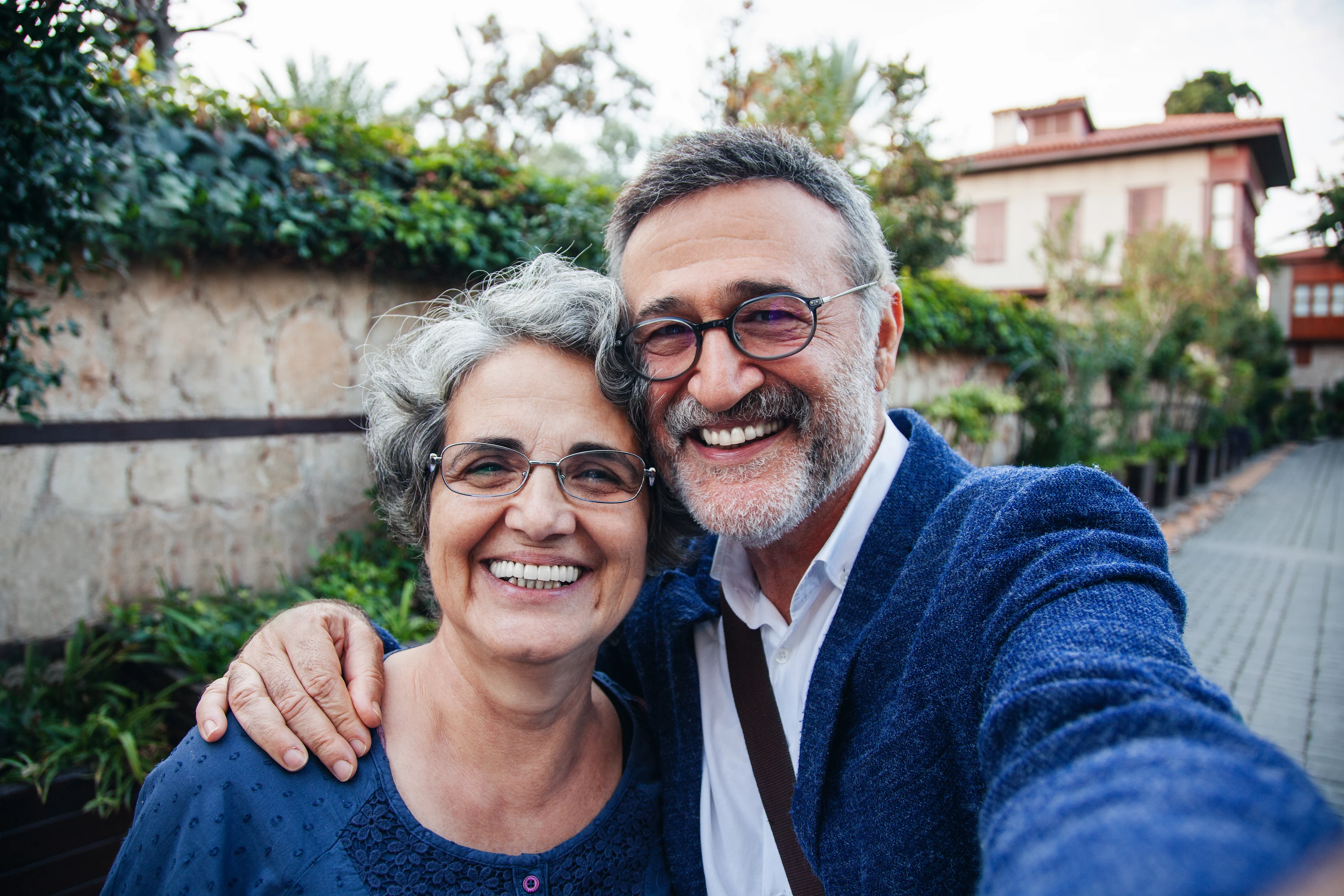 A couple wearing blue is outdoors, smiling for a selfie.