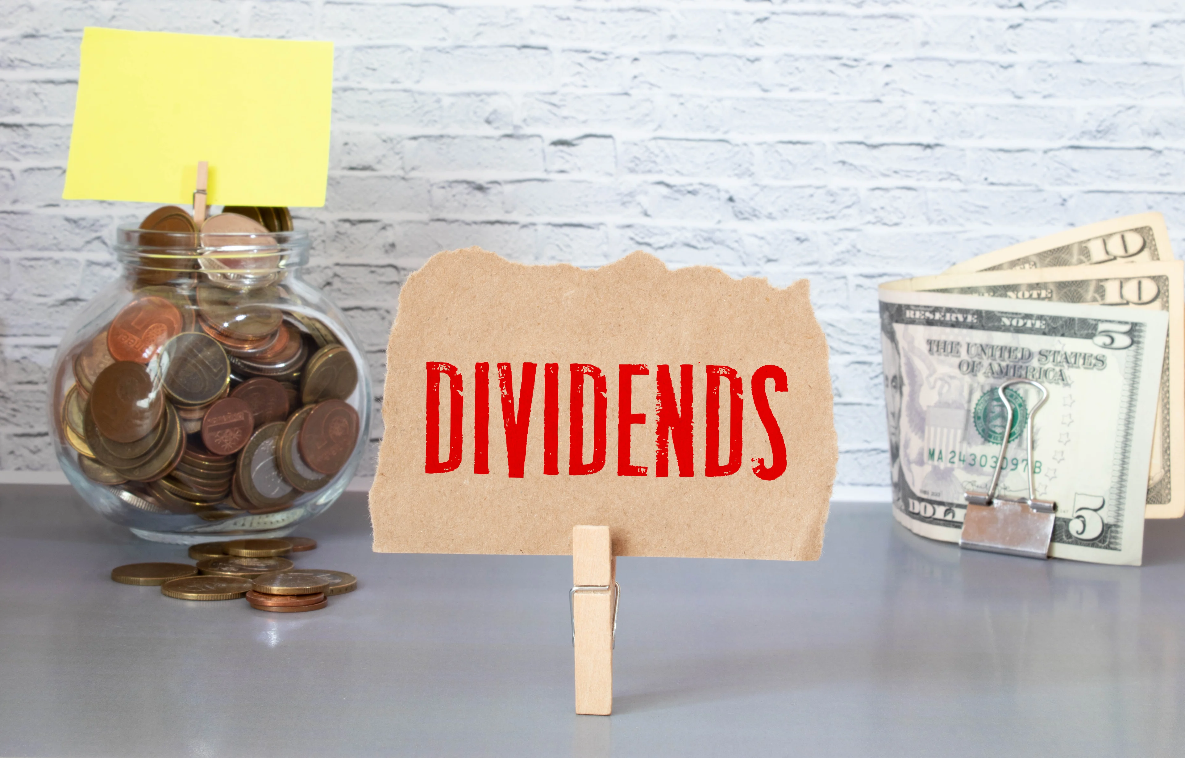 Jar of coins, dollar bills, and a sign that says "dividends."