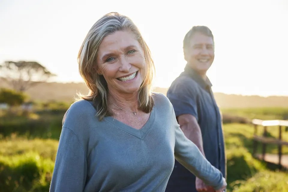 Smiling mature woman and her husband walking outside in summer