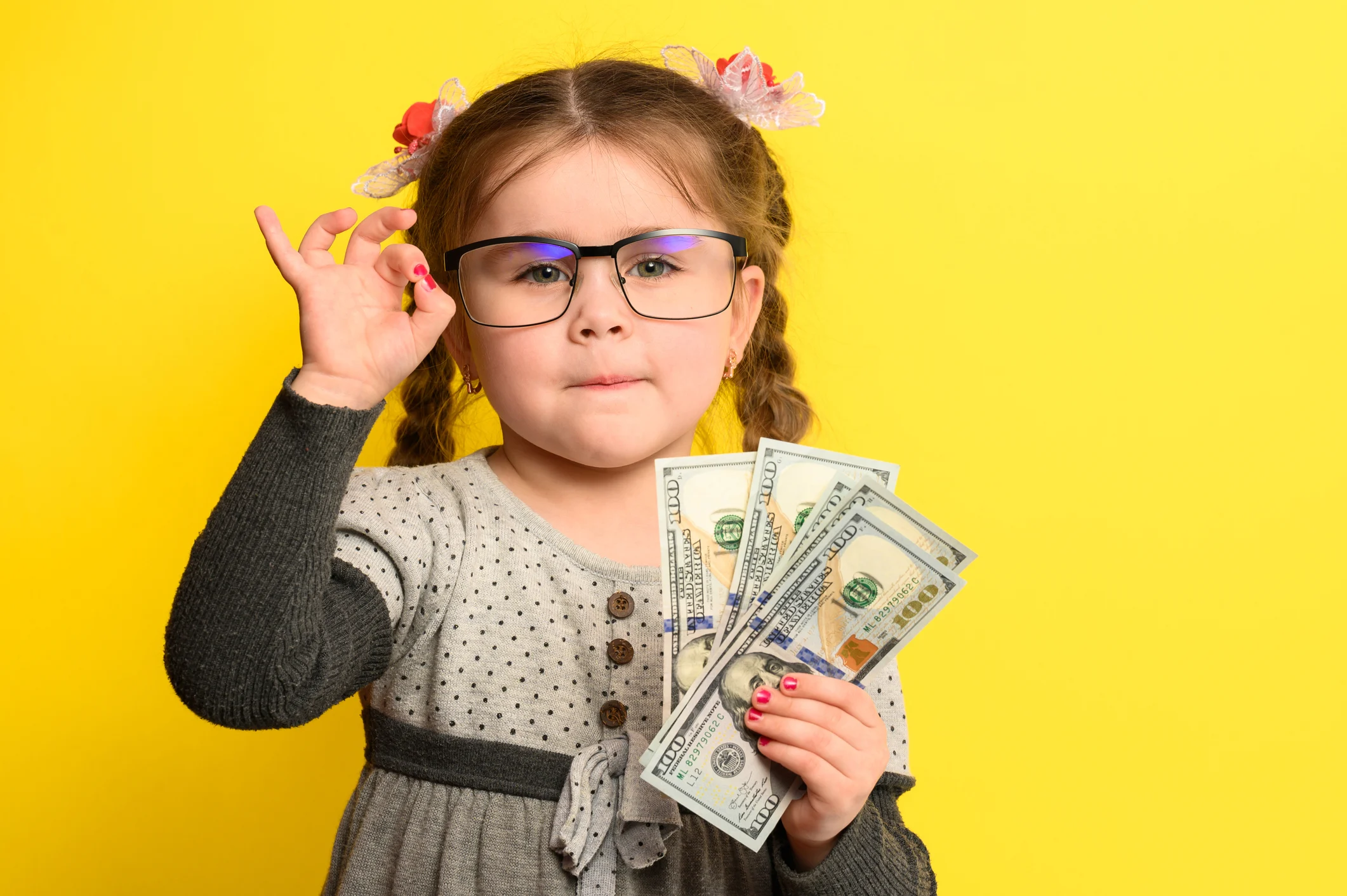 A child is wearing glasses and holding some cash in their hand.