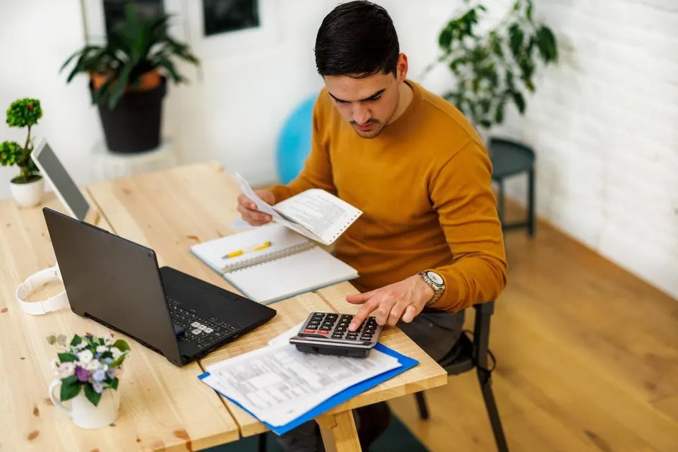 A young man at a home office is researching the best low risk investments for 2026.