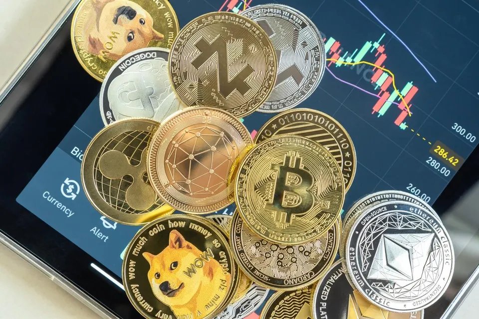 A pile of crypto coins above stock charts for the topic of what is a crypto etf?