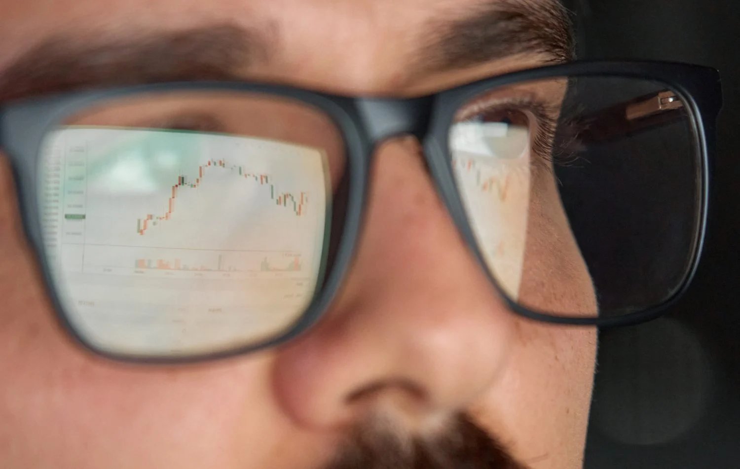 Business man trader broker analyst investor analyzing stock exchange trade crypto financial market looking at computer screen wearing glasses with stockmarket digital chart reflection, close up view.