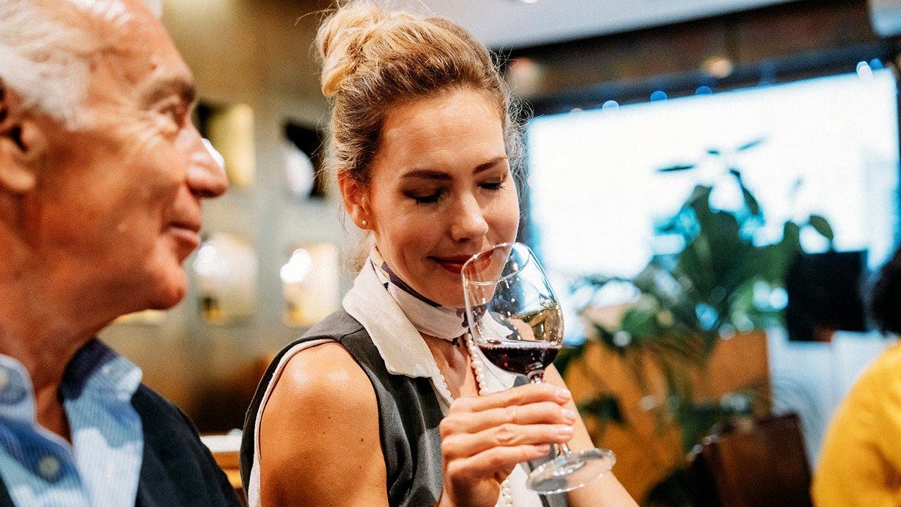 A woman sips a glass of red wine.