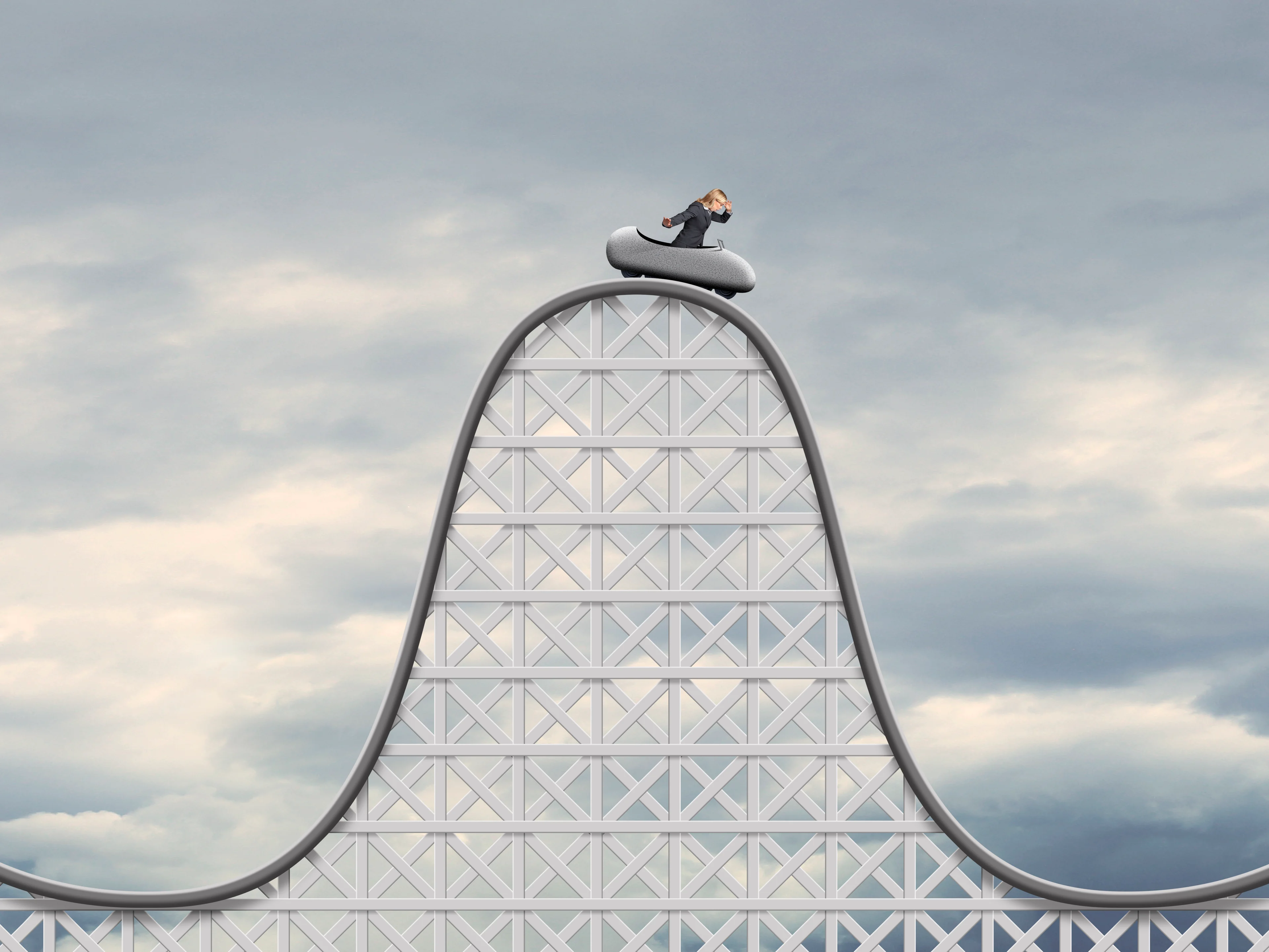 Rollercoaster with person in car at top of hill.