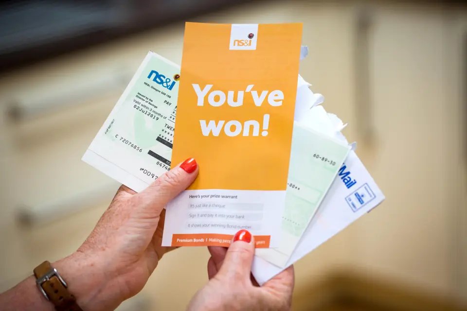 A woman opening a winning Premium Bonds letter with her winners cheque